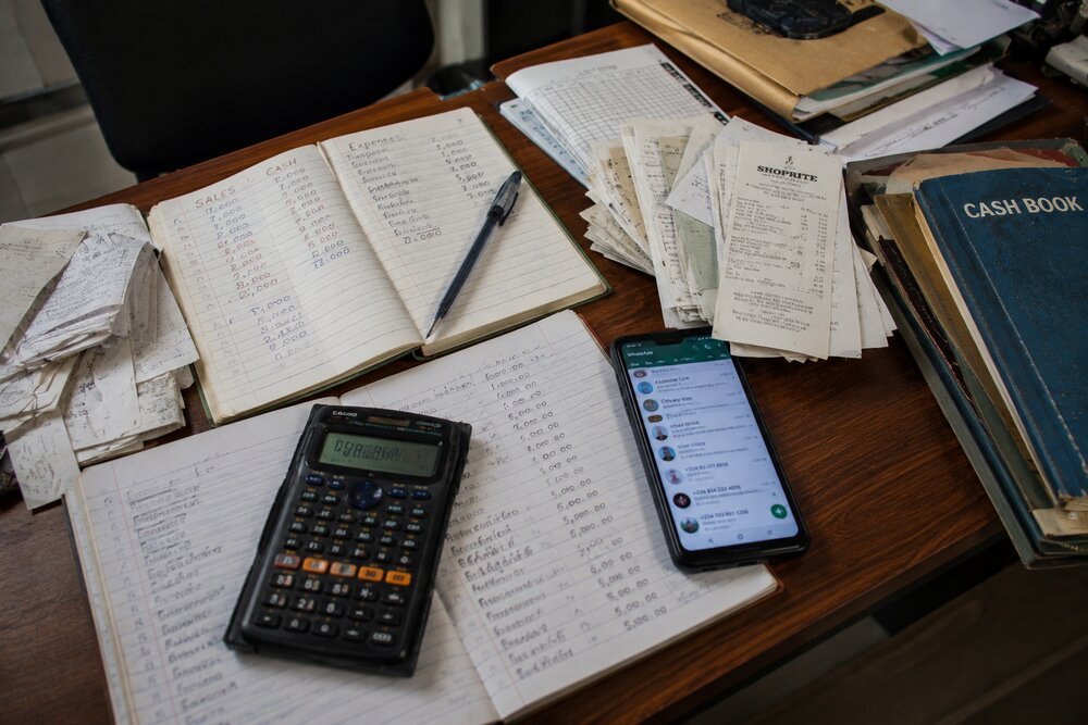 Handwritten sales and expense records, receipts, and a cash book on a desk